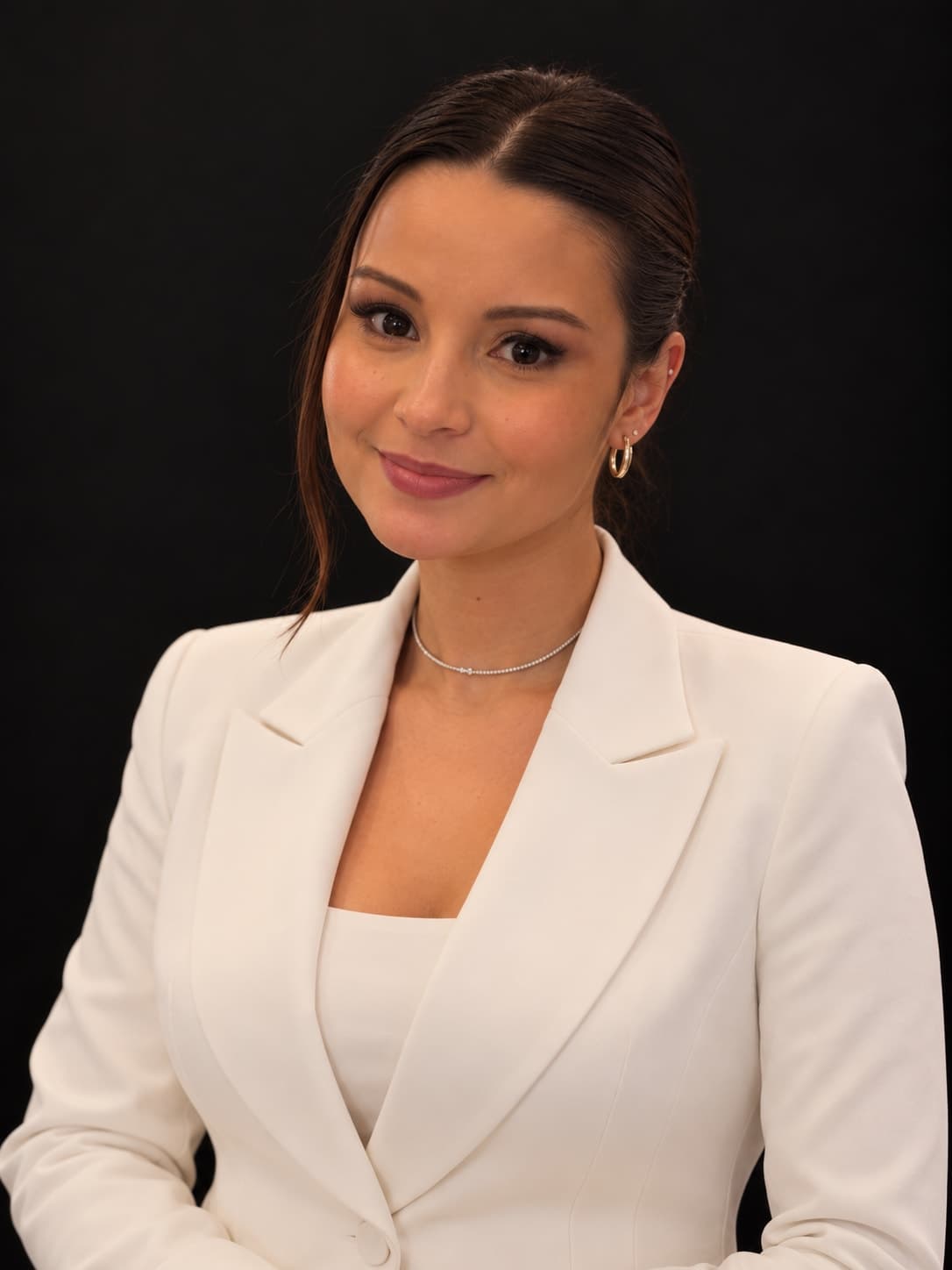 Bárbara Medeiros em retrato de estúdio com blazer branco, sobre fundo escuro